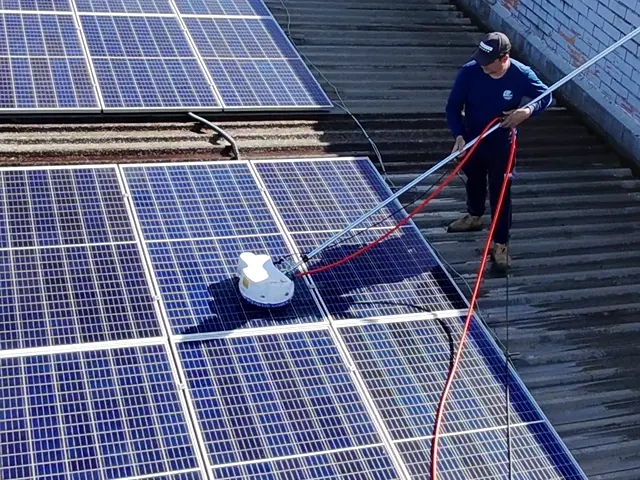 Técnicos da Freu Energia limpando os módulos solares de um telhado, vistos de cima