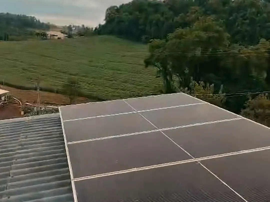 Sistema solar instalado num telhado por uma obra da Freu Energia, com a lavoura ao fundo
